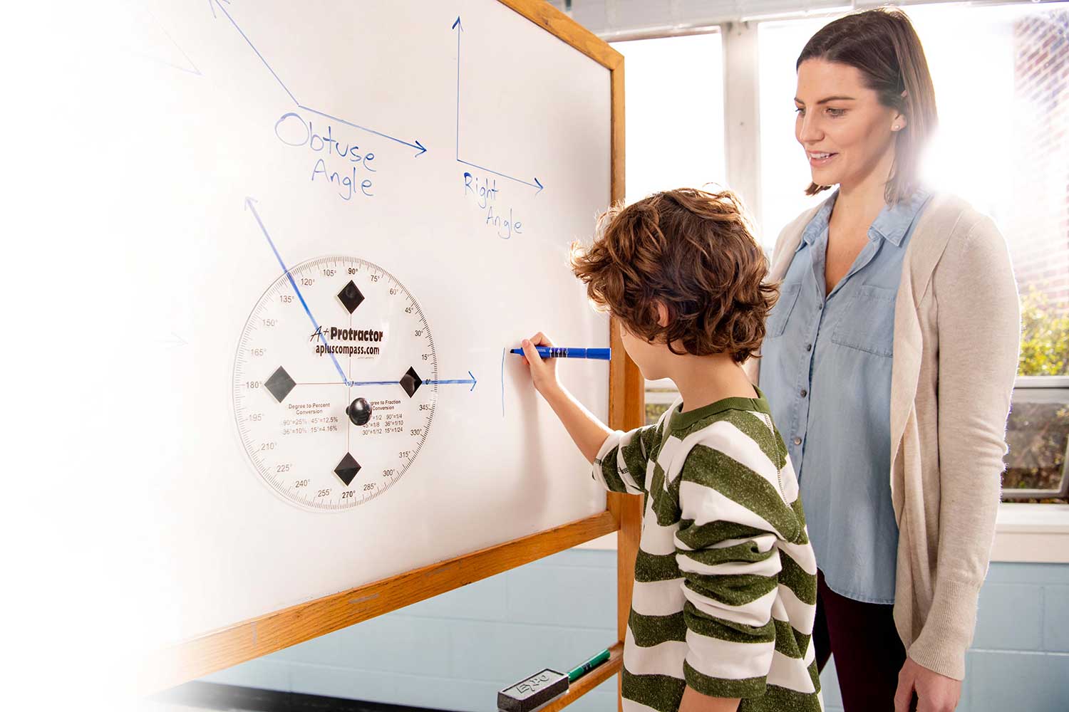 Student uses large protractor at a whiteboard to demonstrate understanding of obtuse and right angles. Student uses large protractor at a whiteboard to demonstrate understanding of obtuse and right angles.