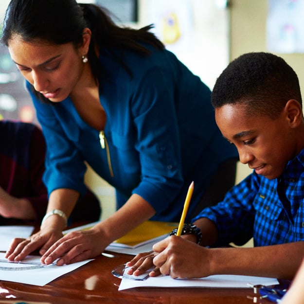 Student working on math homework with teacher.