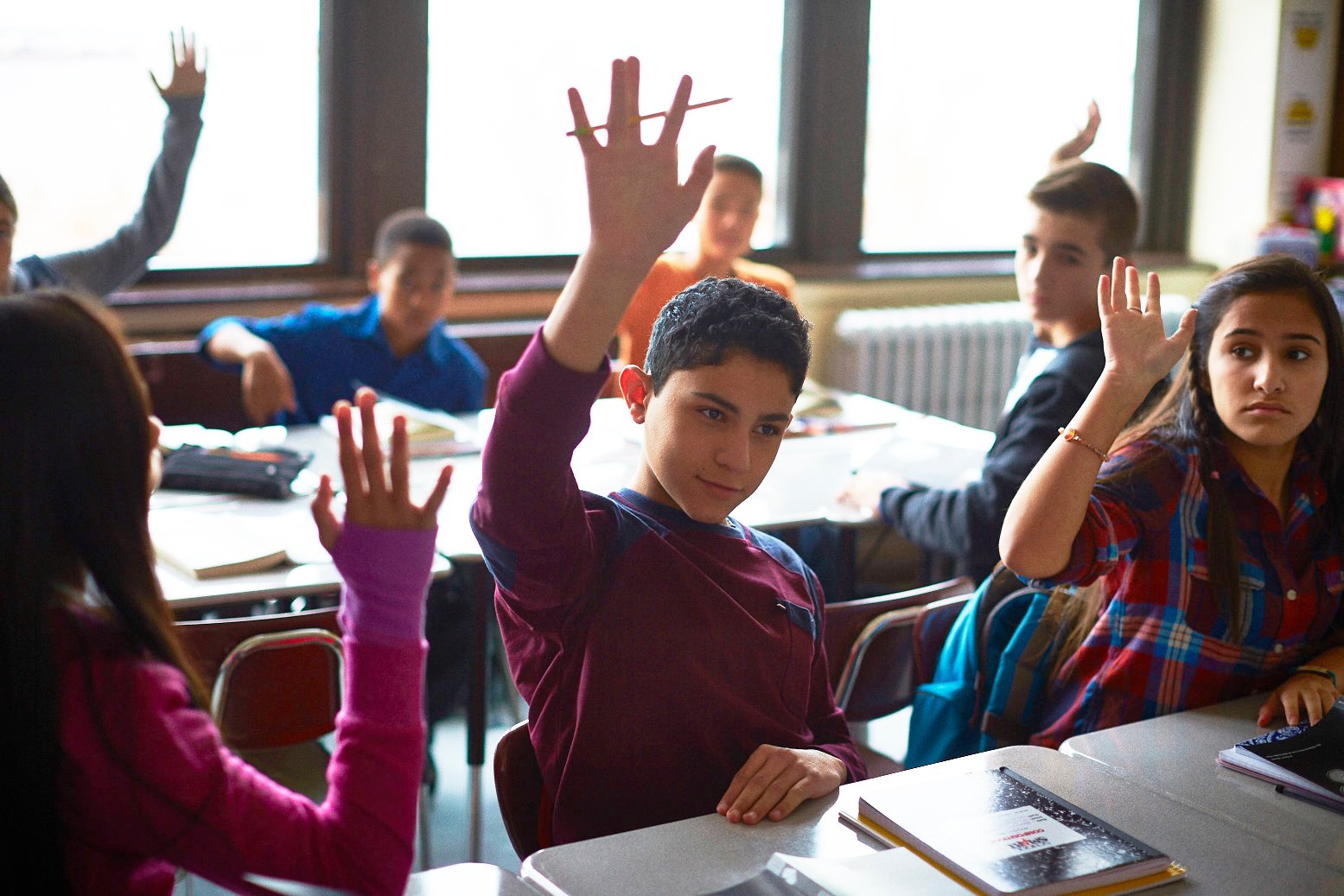Students raising hands in class. Students raising hands in class.
