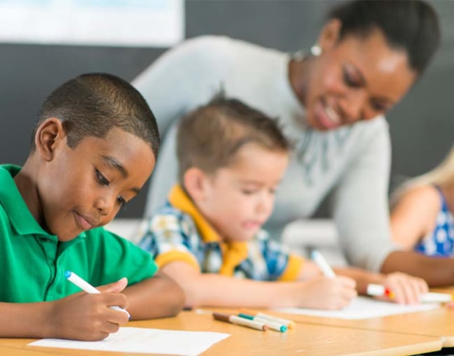 Students writing in class with teachers guidance-2 Students writing in class with teachers guidance-2