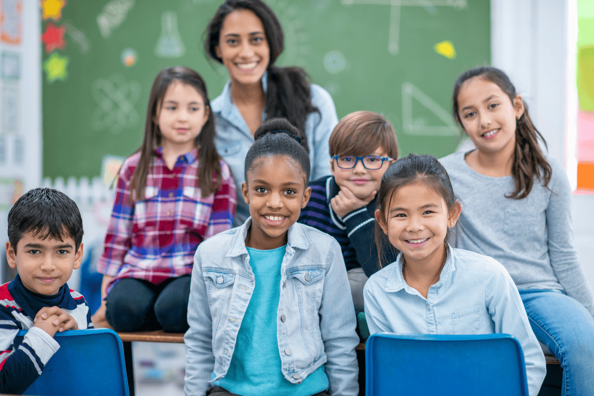 Teacher with a group of students and a blackboard in the background Teacher with a group of students and a blackboard in the background
